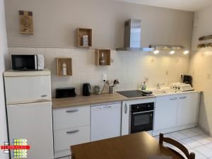 a kitchen with white appliances and a table in it at Echoppe Ancienne Boutique de cordonnier avec jardin privé in Aubeterre-sur-Dronne