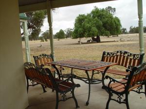 una mesa y cuatro sillas en un porche con un campo en Sylvania Park, en Horsham