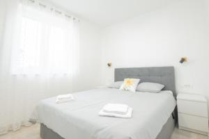a white bedroom with a large bed with towels on it at Apartman Turcic in Malinska