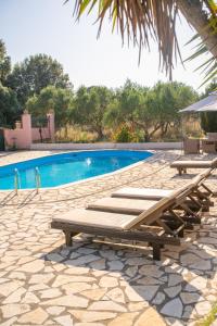 a swimming pool with wooden benches next to at Villa Argias Halikounas in Halikounas