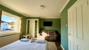 a bedroom with green walls and a bed and a window at Lomond Park Hotel in Balloch