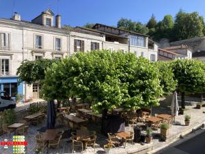 a group of tables and trees in front of a building at Echoppe Ancienne Boutique de cordonnier avec jardin privé in Aubeterre-sur-Dronne