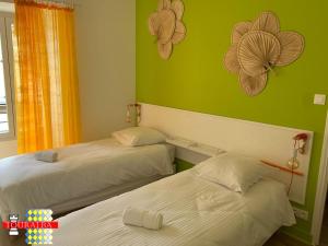 two beds in a room with green walls at Barque Fleurie Maison Retro avec Jardin et Parking au coeur d'Aubeterre-sur-Dronne in Aubeterre-sur-Dronne