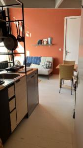 a kitchen with orange walls and a room with a bed at La Boulangerette - Studio in Kralingen in Rotterdam