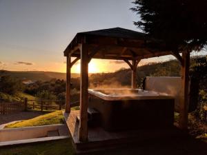 a wooden gazebo with the sunset in the background at The Roost in Saltash +2 photos