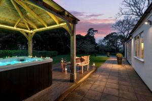 a patio with a hot tub under a pergola at The Estate in Saltash