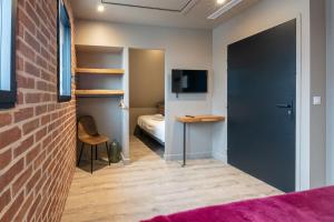 a room with a bedroom with a bed and a brick wall at La Briqueterie in Saint-Aubin