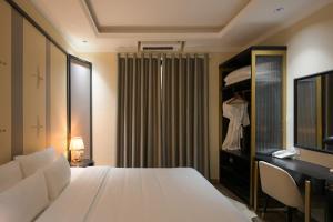 a bedroom with a white bed and a dresser and a mirror at San Hotel & Pool in Hanoi