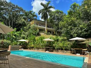 a swimming pool with tables and umbrellas in front of a resort at Hotel La Casablanca Tayrona in Calabazo