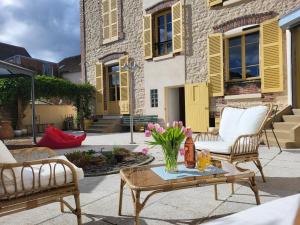 eine Terrasse mit zwei Stühlen und einem Tisch mit Blumen in der Unterkunft L'Armancine, chambres d'hôtes in Saint-Florentin