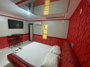 a room with a bed and a red wall at Hotel Master Blue - Brasília in Ceilândia