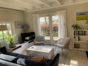 a living room with a couch and chairs and a tv at Gastenverblijf Oostdijk in Goedereede