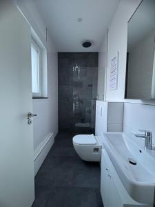 a white bathroom with a toilet and a sink at City Lounge Bielefeld 005 in Bielefeld