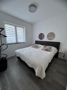 a bedroom with a bed with white sheets and two windows at City Lounge Bielefeld 005 in Bielefeld