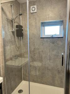 a shower with a glass door and a window at Bossiney Lodge Apartment in Tintagel +19 photos