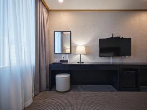 a hotel room with a desk with a tv and a mirror at 퀸벨호텔 in Tōson