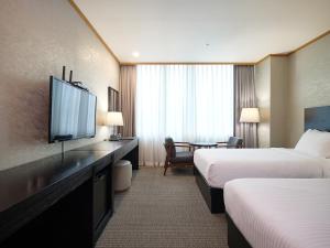 a hotel room with two beds and a flat screen tv at 퀸벨호텔 in Tōson +41 photos