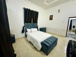 a bedroom with a white bed and a blue chair at Resmay apartment in Abuja
