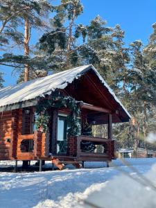 a cabin with a snow covered roof in the snow at Spokiy in Glebovka