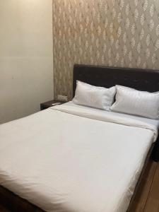 a bed with white sheets and pillows in a bedroom at Hotel Grants Residency Colaba in Mumbai