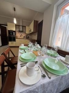 a dining room table with green plates and wine glasses at Tessa Central House in Kőszeg