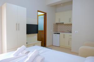 a white bedroom with a white bed and a kitchen at Vila Balani in Ksamil