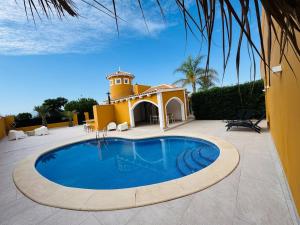 a swimming pool in front of a building with a lighthouse at Casa Indigo Mazarron in Mazarrón