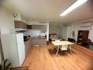 a kitchen with a wooden table and a white refrigerator at Studio Piscine à Saint-Gilles prés des plages in L'Ermitage-Les-Bains