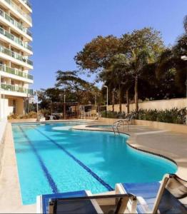 a large swimming pool with chairs and a building at Rio Stay Suíte in Rio de Janeiro