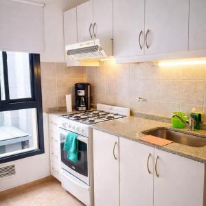 a white kitchen with a stove and a sink at Departamento CBA in Córdoba