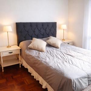 a bedroom with a bed with two night tables and two lamps at Departamento CBA in Córdoba