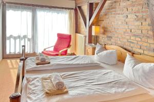 a hotel room with two beds and a red chair at Altstadtflair - Rüster in Lübbenau