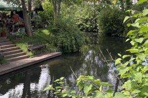 a river with a wooden bridge and a bench in a park at Libelle in Lübben