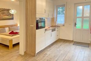 a kitchen with white cabinets and a couch in a room at Holzfäller Baum 2 in Burg