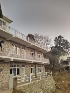 a building with a balcony on the side of it at The pine view Orchard homestay in Rāmgarh