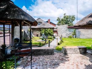 a garden with a stone building and an umbrella at Bostons Lodge & Restaurant in Jan Kempdorp