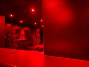 a red bathroom with a tub and a mirror at Love Room- Jacuzzi XXL- Climatisé- Table massage Accessoires in LʼEscarène