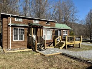 a small wooden cabin with a porch and a deck at Maggie Valley Cabin Rentals in Maggie Valley