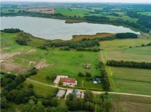 an aerial view of a field with a house and a lake at Det lille hus in Viborg
