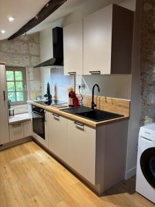 a kitchen with white cabinets and a sink at gite 3 le havre in Aubeterre-sur-Dronne