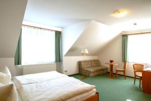 a bedroom with a bed and a chair and a table at Pension Seeluft in Ahrenshoop