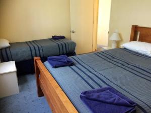 two beds in a hotel room with purple towels on them at Cedar Chalets in Methven