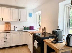 a kitchen with white cabinets and a black stove top oven at By The Bay A Thatched House Lies So Beautifully in Nørre Åby