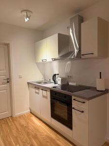 a kitchen with white cabinets and a stove top oven at Cozy Studio Residenz Platz 1 near Neues Schloss Bayreuth in Bayreuth +5 photos