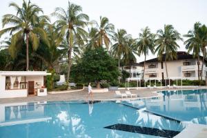a person walking in a swimming pool with palm trees at VOI Kiwengwa Resort in Kiwengwa
