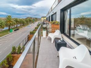 a balcony with white chairs and a view of a street at Alojamientos Marte apartamento a pie de playa y garaje in Suances