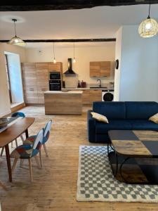 a living room with a blue couch and a kitchen at gite 4 le refuge in Aubeterre-sur-Dronne