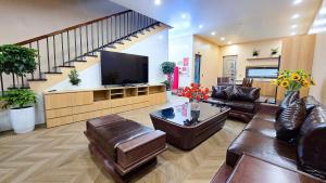 a living room with leather furniture and a flat screen tv at Ha Anh Villa Ninh Binh in Ninh Binh