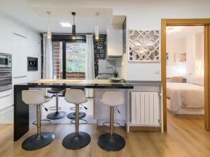 a kitchen with three bar stools and a kitchen with a bed at Alojamientos Marte apartamento a pie de playa y garaje in Suances