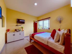 a bedroom with yellow walls and a bed with red pillows at Kodai Hillscape in Kodaikānāl